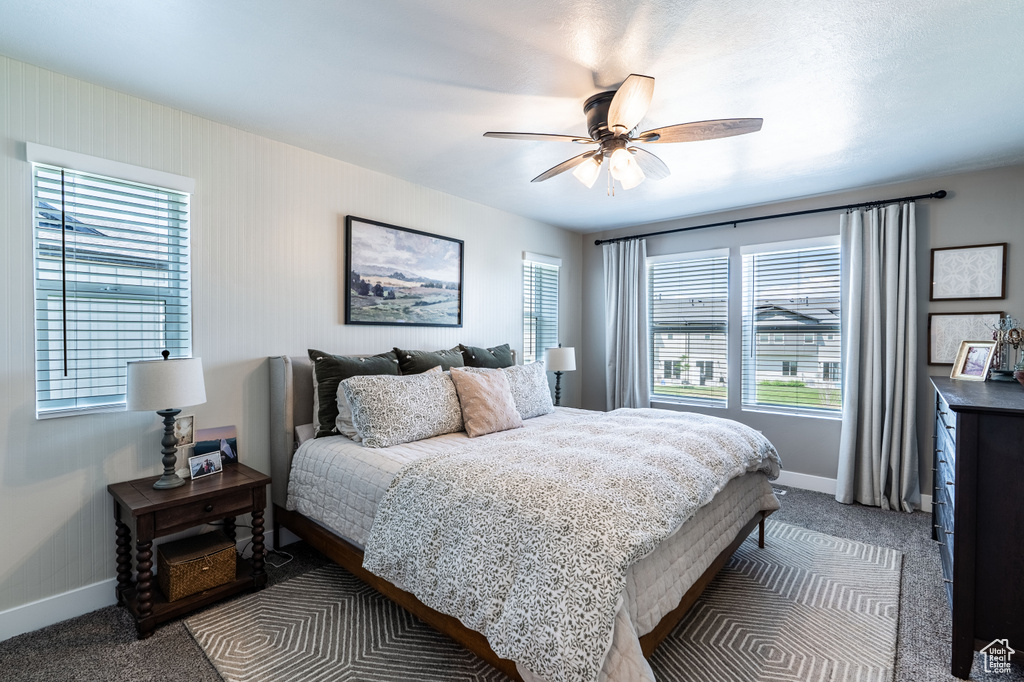 Bedroom featuring baseboards, multiple windows, and dark colored carpet