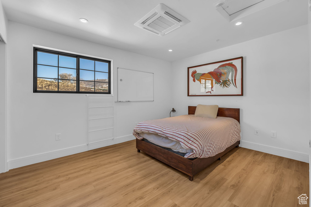 Bedroom featuring baseboards, light wood finished floors, recessed lighting, and attic access