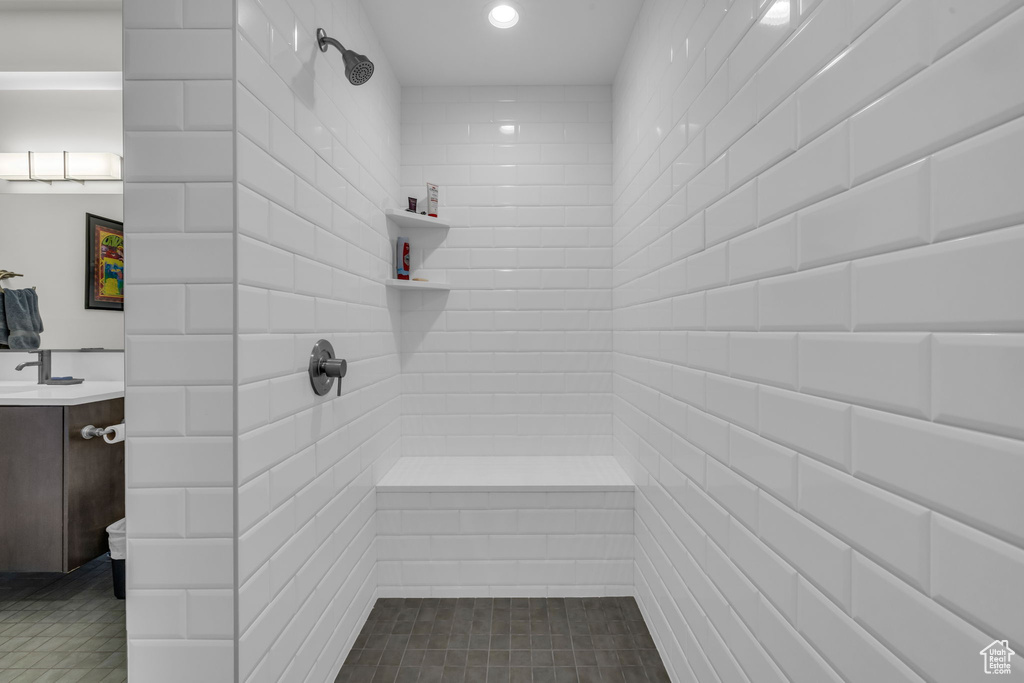 Full bathroom featuring tiled shower, vanity, and recessed lighting