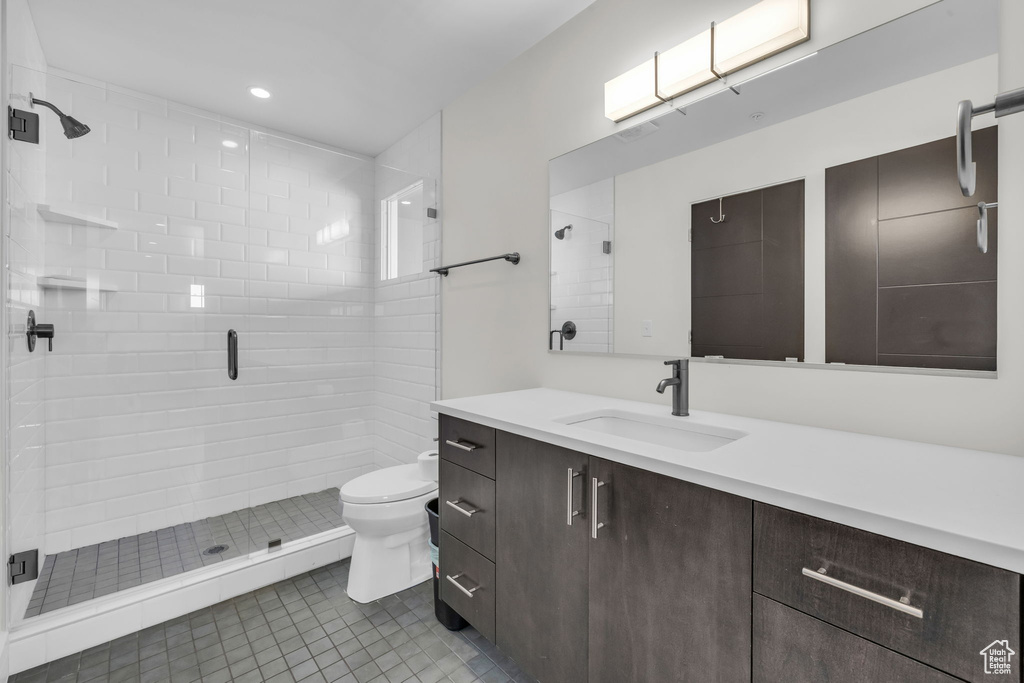 Full bathroom featuring toilet, a stall shower, vanity, tile patterned floors, and recessed lighting