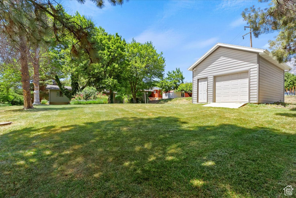 View of grassy yard with a garage and an outdoor structure