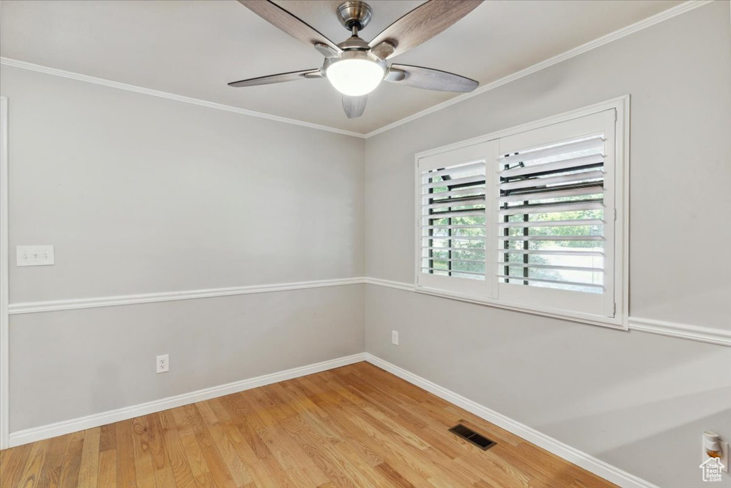 Spare room featuring baseboards, light wood-style floors, a ceiling fan, and ornamental molding
