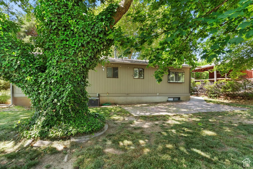 Rear view of property featuring a patio area, central air condition unit, and a yard
