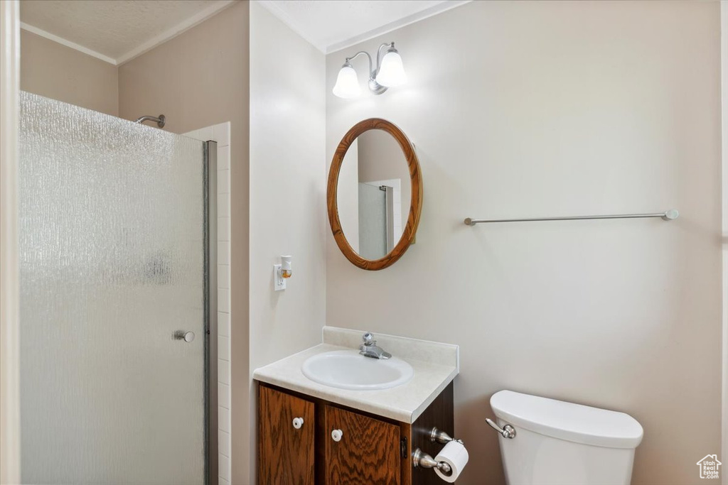 Bathroom featuring a stall shower, toilet, vanity, and ornamental molding