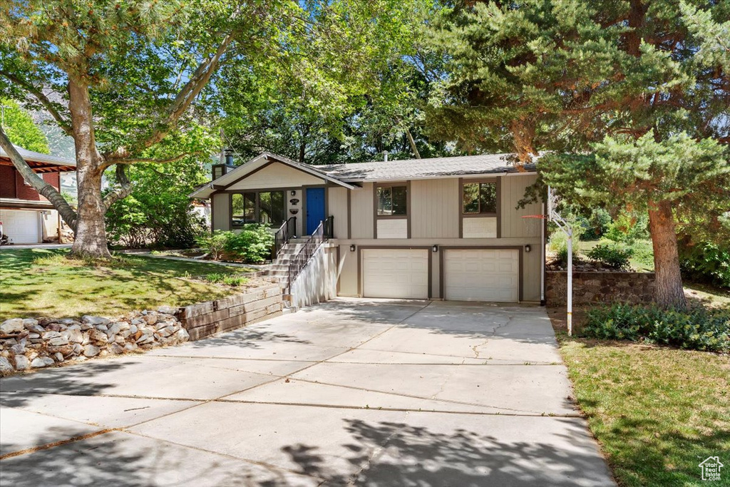 View of front of home with an attached garage, concrete driveway, and a front lawn