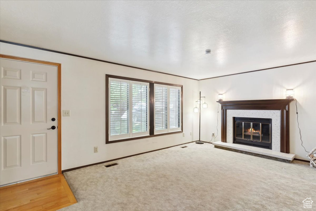 Unfurnished living room with a glass covered fireplace, baseboards, and carpet flooring