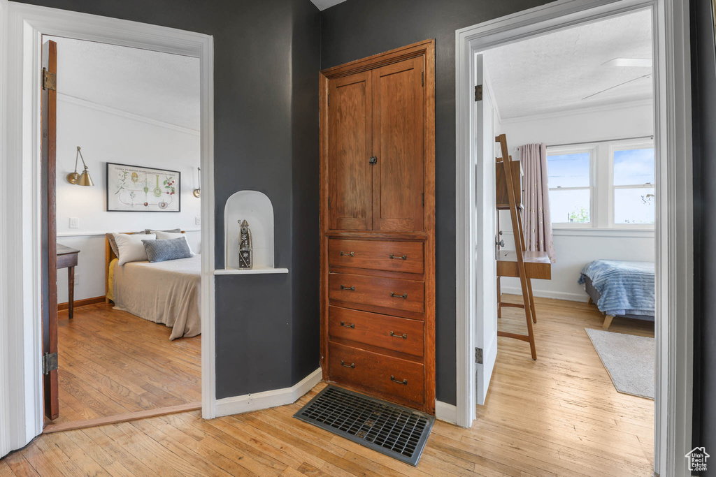 Bedroom featuring light wood-style flooring, ornamental molding, and baseboards