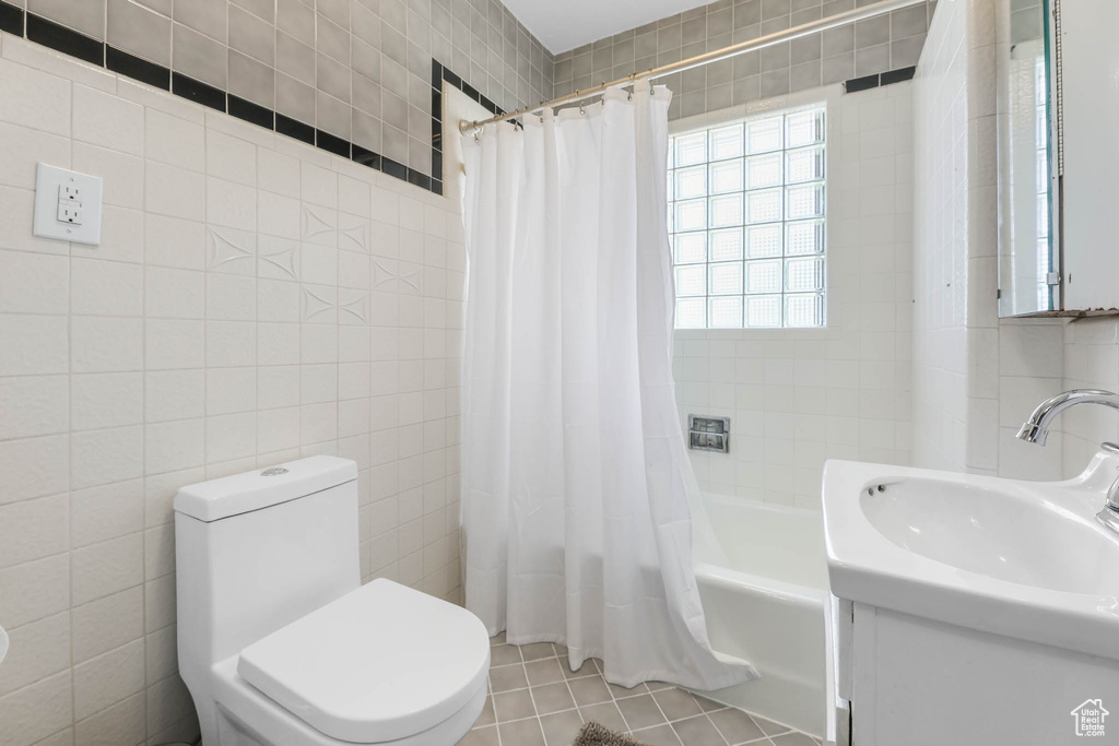 Full bathroom featuring tile walls, shower / bathtub combination with curtain, toilet, tile patterned floors, and vanity