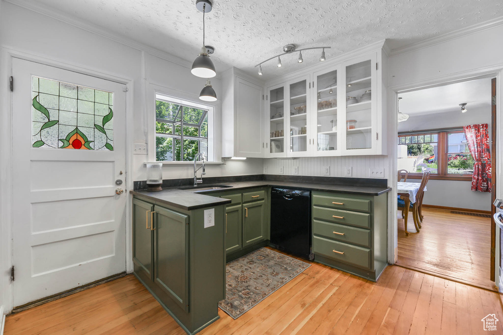 Kitchen with green cabinets, black dishwasher, a sink, dark countertops, and crown molding