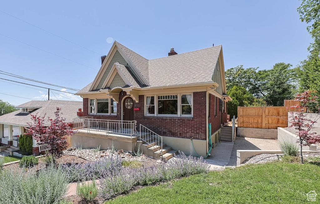View of front of property with a shingled roof, a chimney, and brick siding