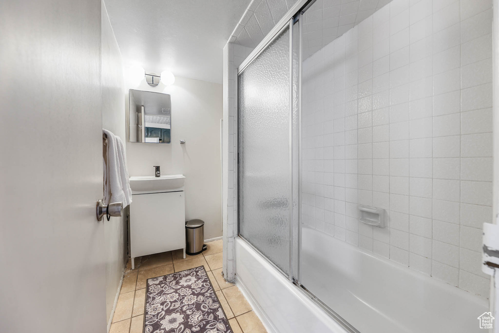 Full bath with tile patterned flooring, vanity, and combined bath / shower with glass door