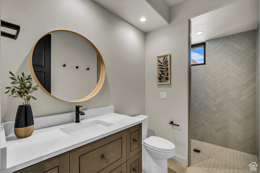 Bathroom with vanity, toilet, tiled shower, and recessed lighting