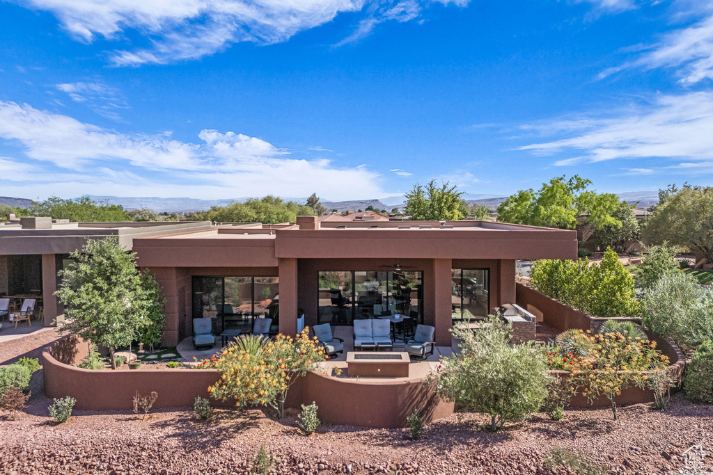 Rear view of property featuring an outdoor living space with a fire pit, a patio, stucco siding, and a mountain view