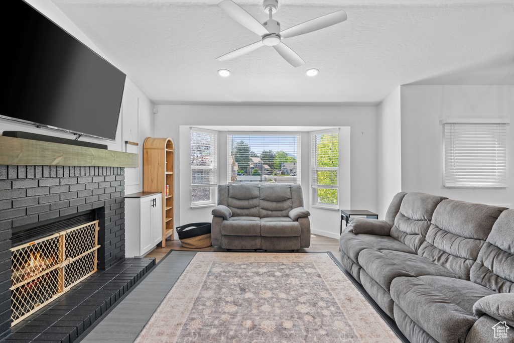 Living room featuring ceiling fan, wood finished floors, a brick fireplace, recessed lighting, and baseboards