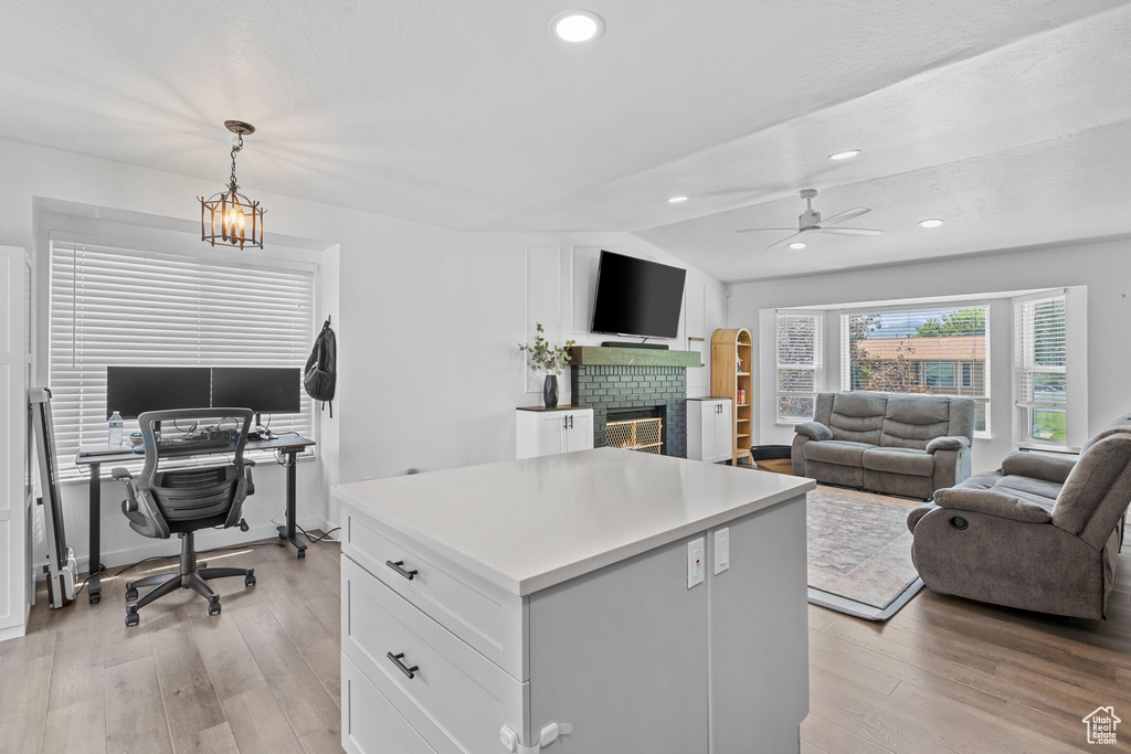 Home office featuring light wood finished floors, ceiling fan, a fireplace, vaulted ceiling, and recessed lighting