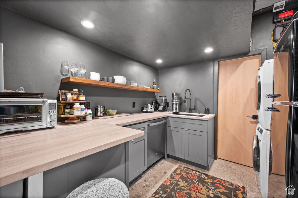 Bar featuring a sink, estacked washer and dryer, dishwasher, and recessed lighting
