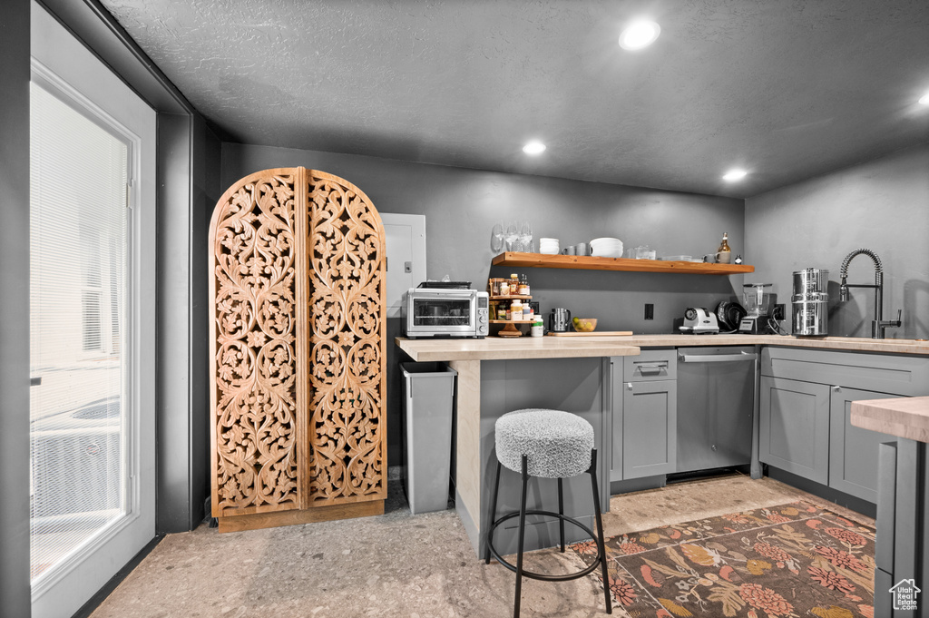 Kitchen featuring stainless steel dishwasher, gray cabinetry, a sink, recessed lighting, and open shelves