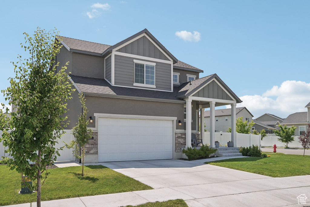 View of front of property with concrete driveway, board and batten siding, a shingled roof, an attached garage, and stucco siding