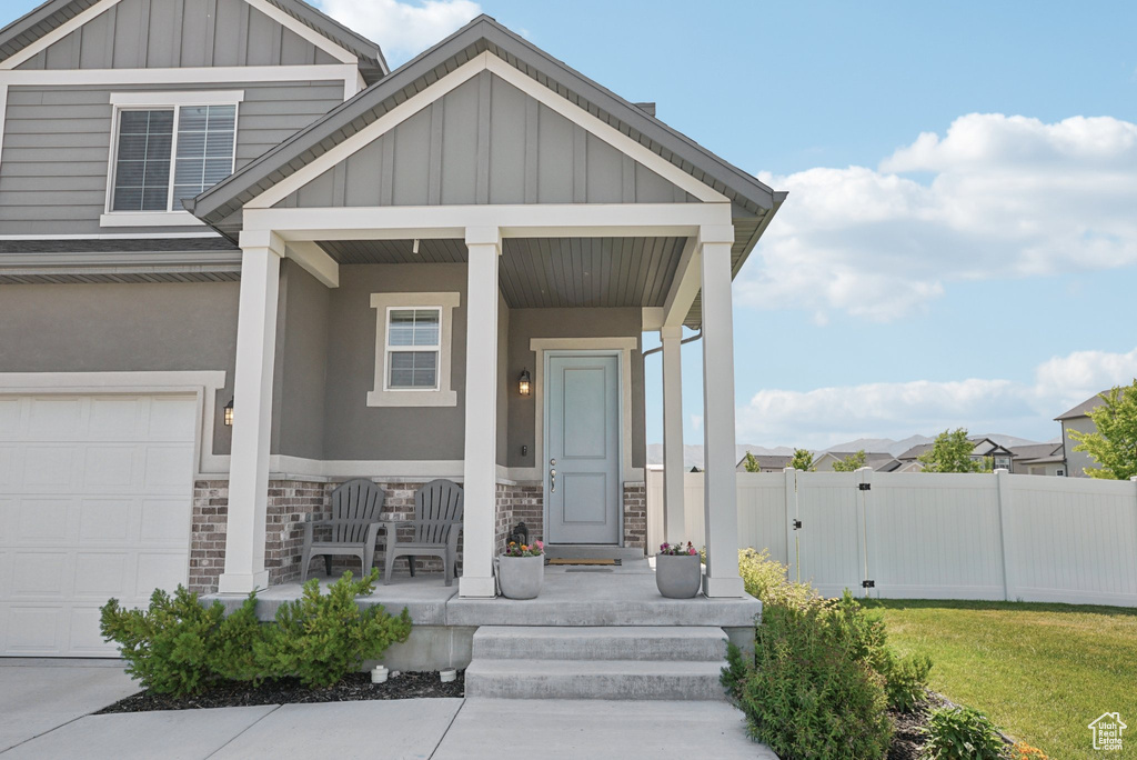 View of front of home featuring a porch, board and batten siding, stone siding, a gate, and a garage