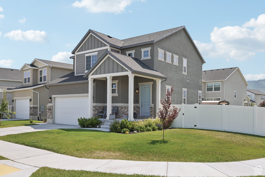 Craftsman-style home with board and batten siding, a porch, driveway, an attached garage, and stone siding