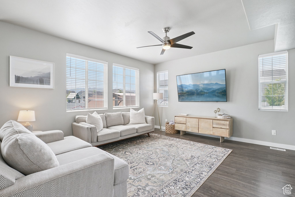Living area with baseboards, a ceiling fan, and dark wood-style floors
