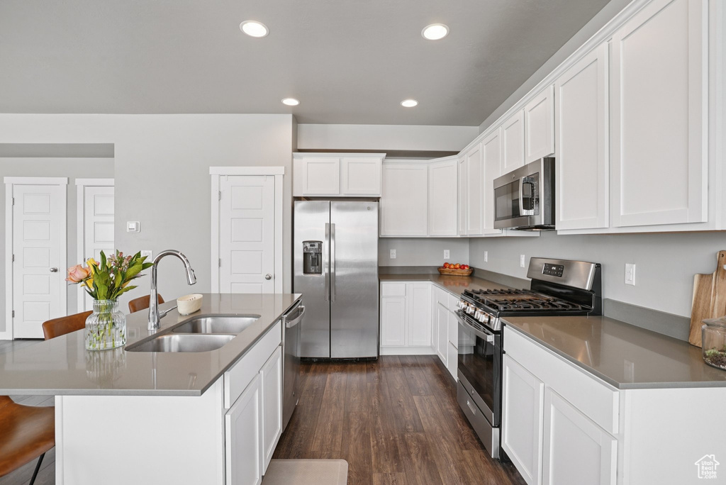 Kitchen featuring appliances with stainless steel finishes, a sink, dark wood finished floors, white cabinets, and recessed lighting