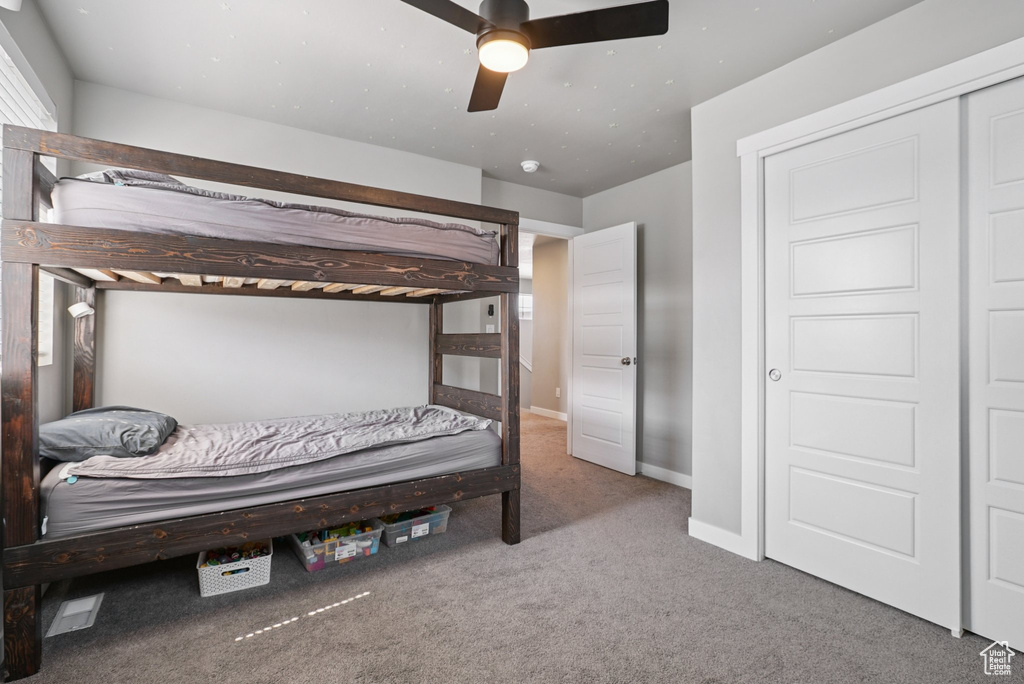 Carpeted bedroom featuring baseboards and ceiling fan
