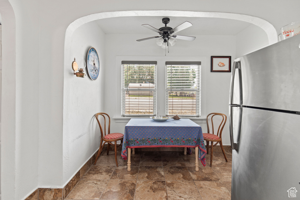 Dining space with baseboards, stone finish flooring, arched walkways, and a ceiling fan