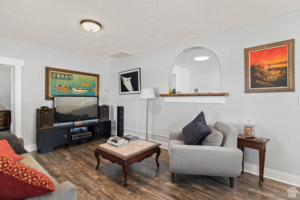 Living room with wood finished floors, baseboards, and arched walkways