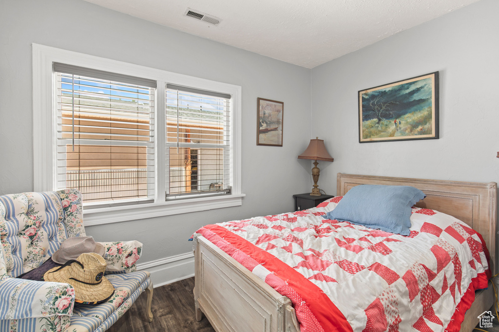 Bedroom with dark wood finished floors and baseboards