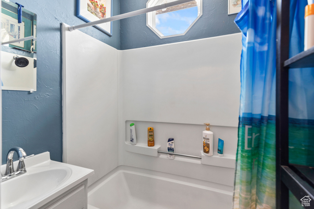 Bathroom featuring a textured wall, vanity, and shower / bath combo with shower curtain