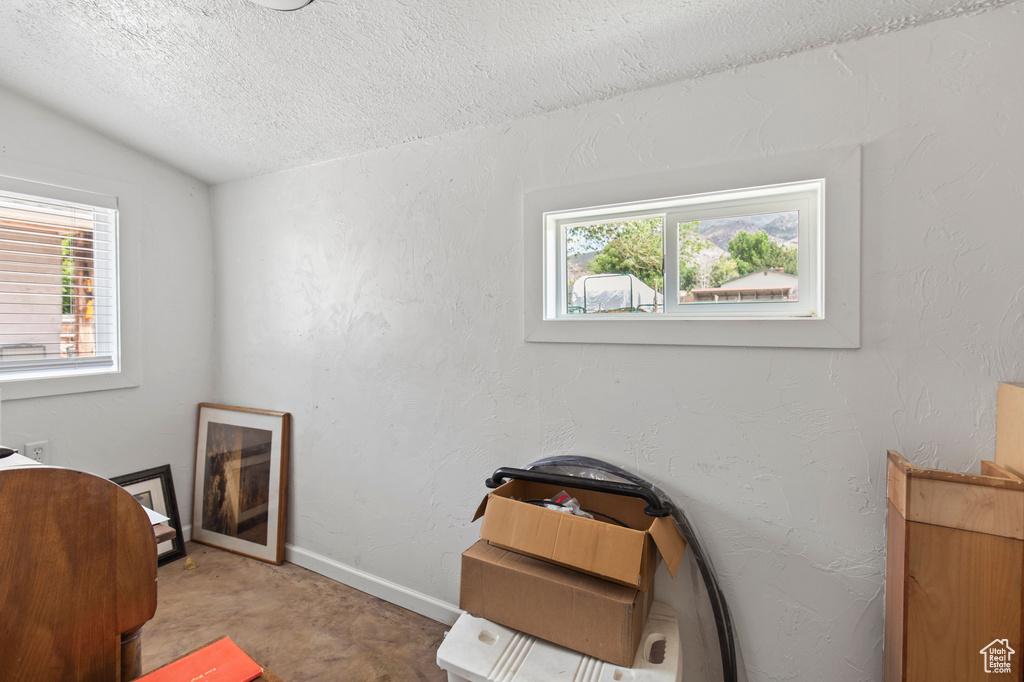 Bedroom with lofted ceiling, a textured ceiling, and baseboards