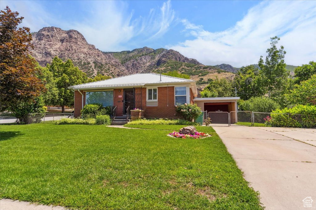 View of front of house with a mountain view, concrete driveway, brick siding, and a carport