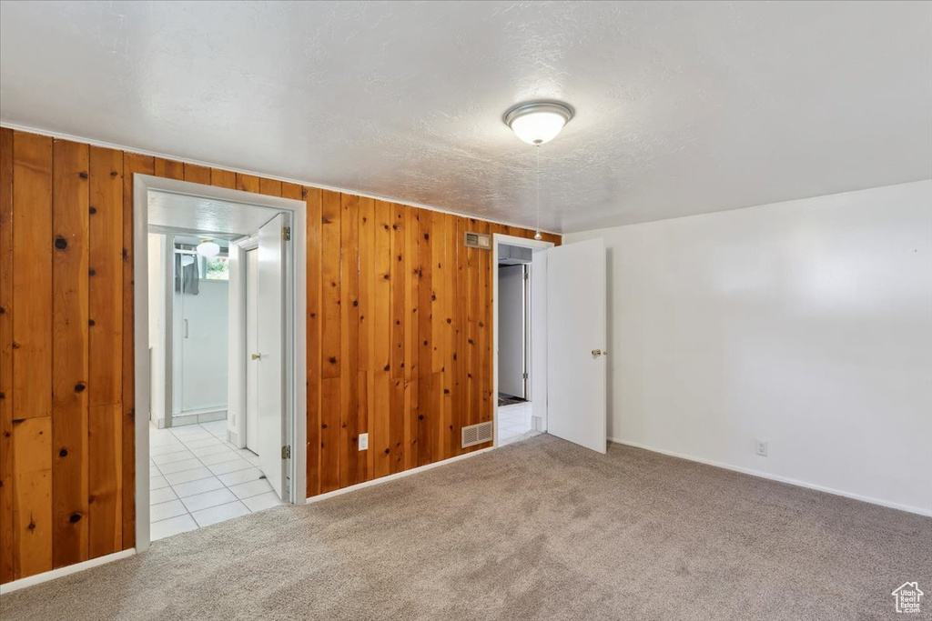 Spare room with carpet flooring, wood walls, and baseboards
