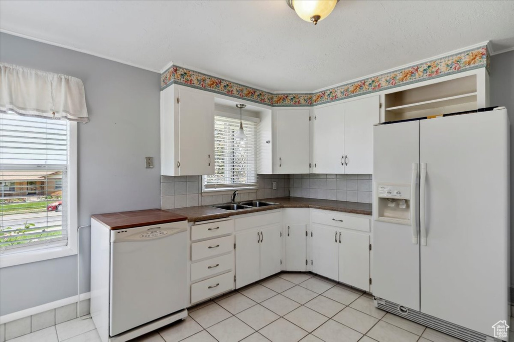 Kitchen featuring white appliances, a sink, dark countertops, and tasteful backsplash