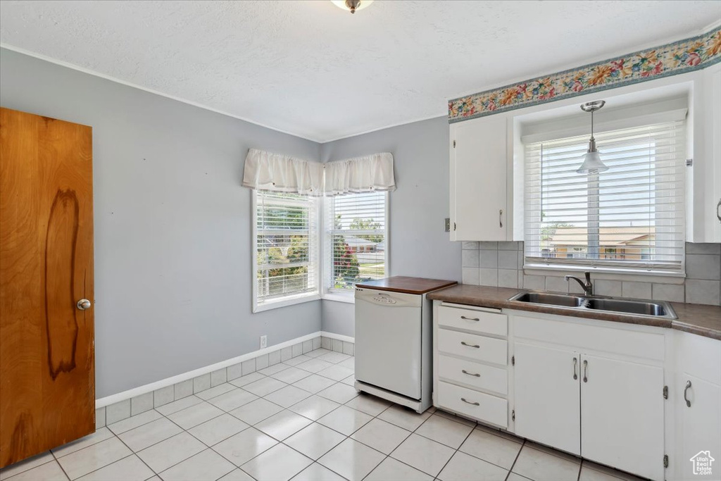 Kitchen featuring white dishwasher, a sink, white cabinetry, backsplash, and baseboards