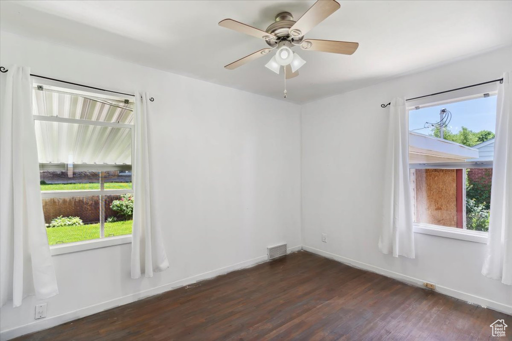 Spare room featuring dark wood-style flooring, baseboards, and a ceiling fan