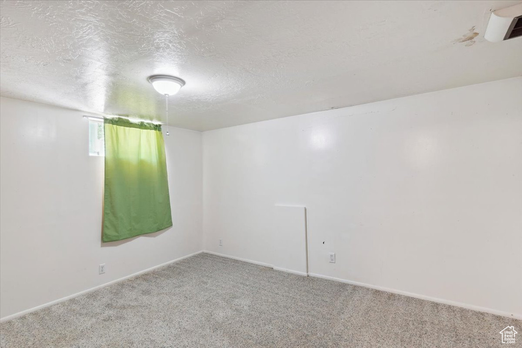 Unfurnished room with carpet, a textured ceiling, and baseboards