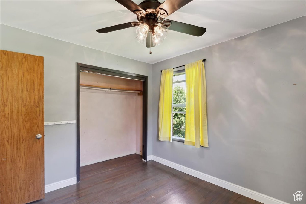 Unfurnished bedroom featuring a closet, baseboards, wood finished floors, and a ceiling fan