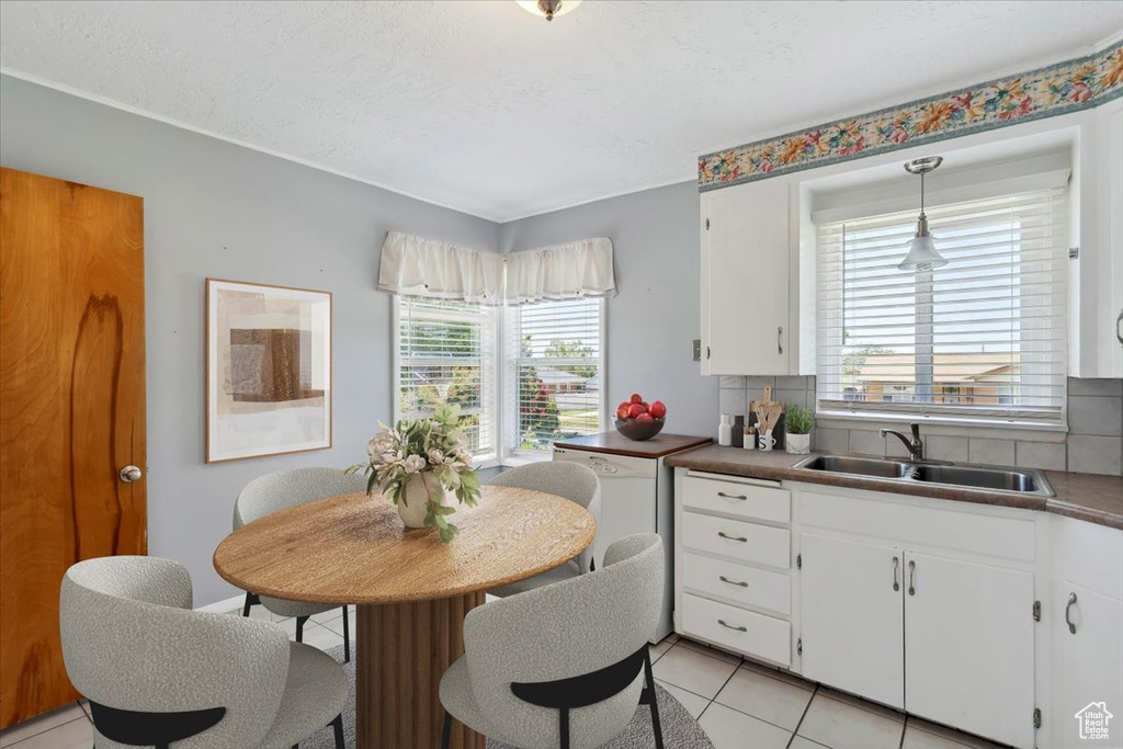 Kitchen with a sink, healthy amount of natural light, white cabinets, and light tile patterned floors