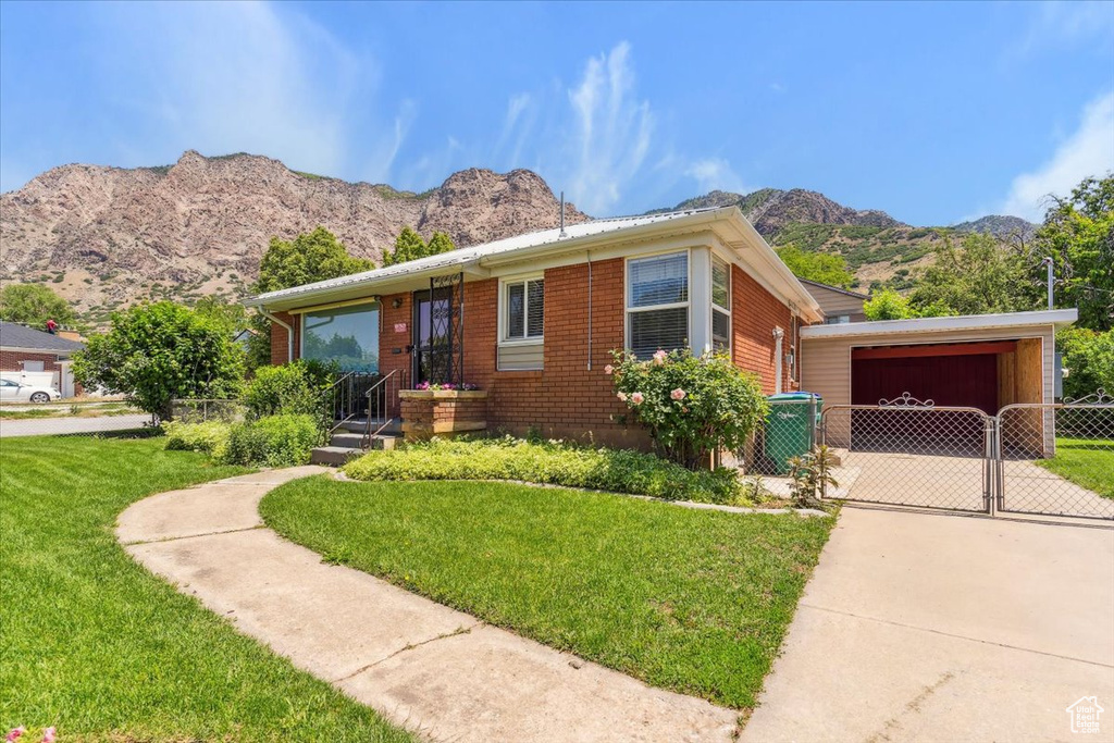 View of front of property featuring a gate, a mountain view, concrete driveway, and a carport