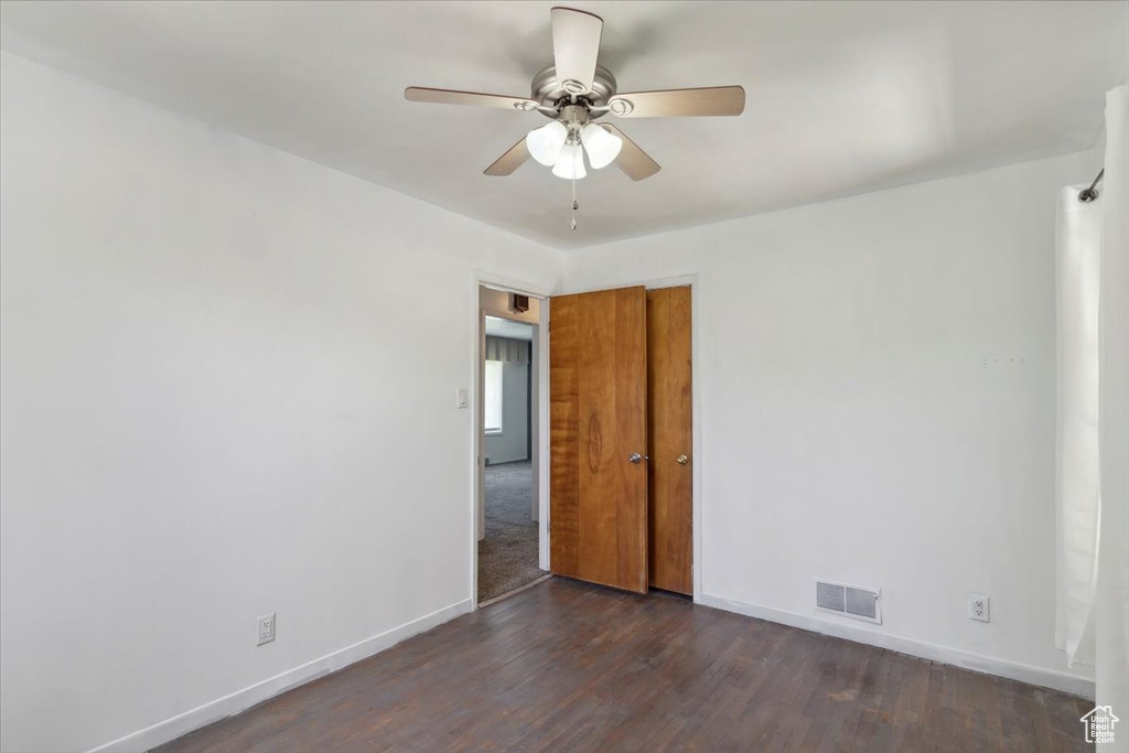Spare room with baseboards, a ceiling fan, and dark wood finished floors