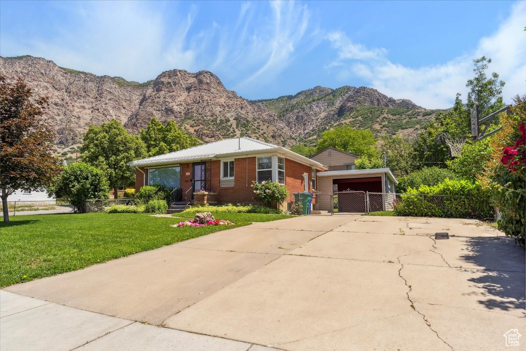 View of front of home featuring driveway, brick siding, a mountain view, and a carport