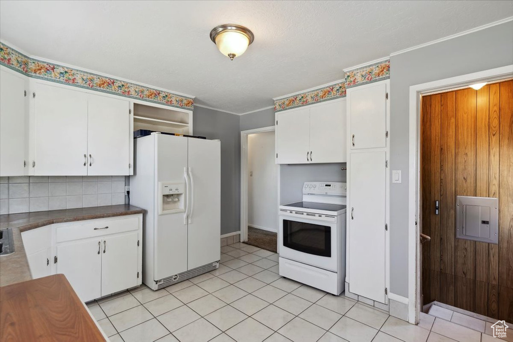 Kitchen featuring white appliances, white cabinets, backsplash, electric panel, and crown molding