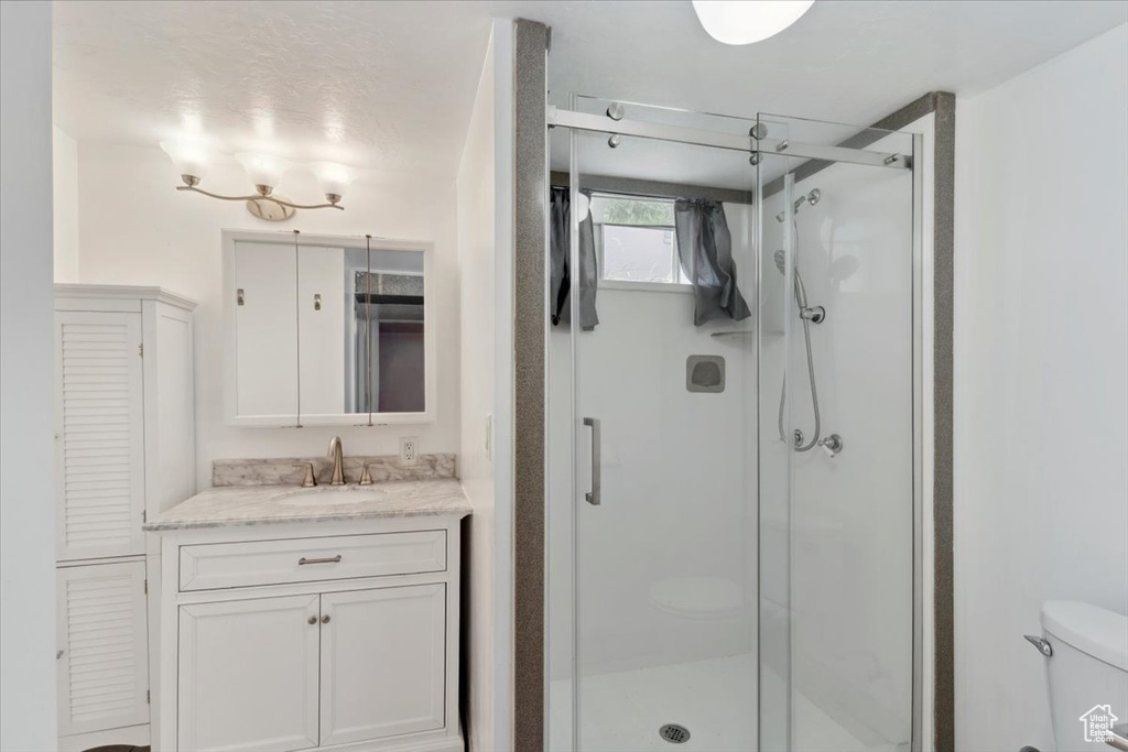 Full bath featuring a shower stall, vanity, toilet, and a closet