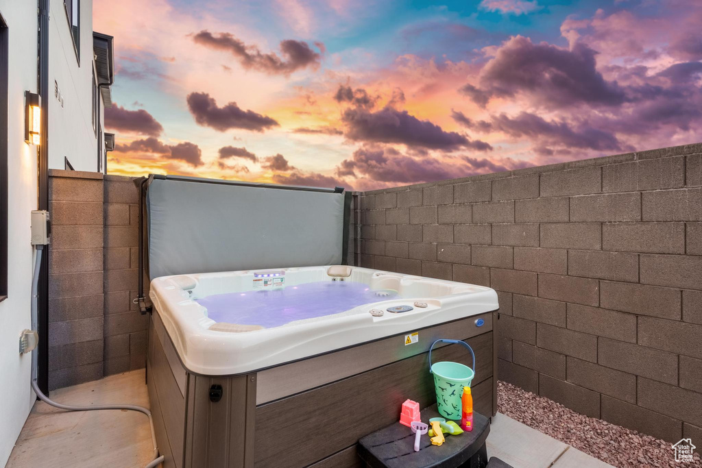 Patio terrace at dusk featuring a hot tub