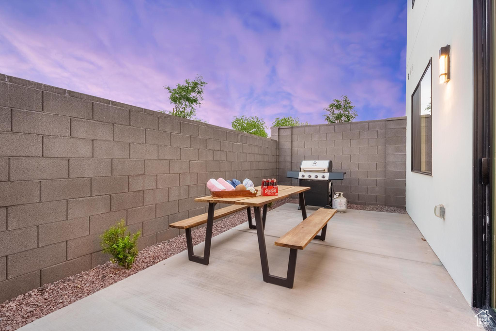 Patio terrace at dusk with a grill, a patio area, and a fenced backyard