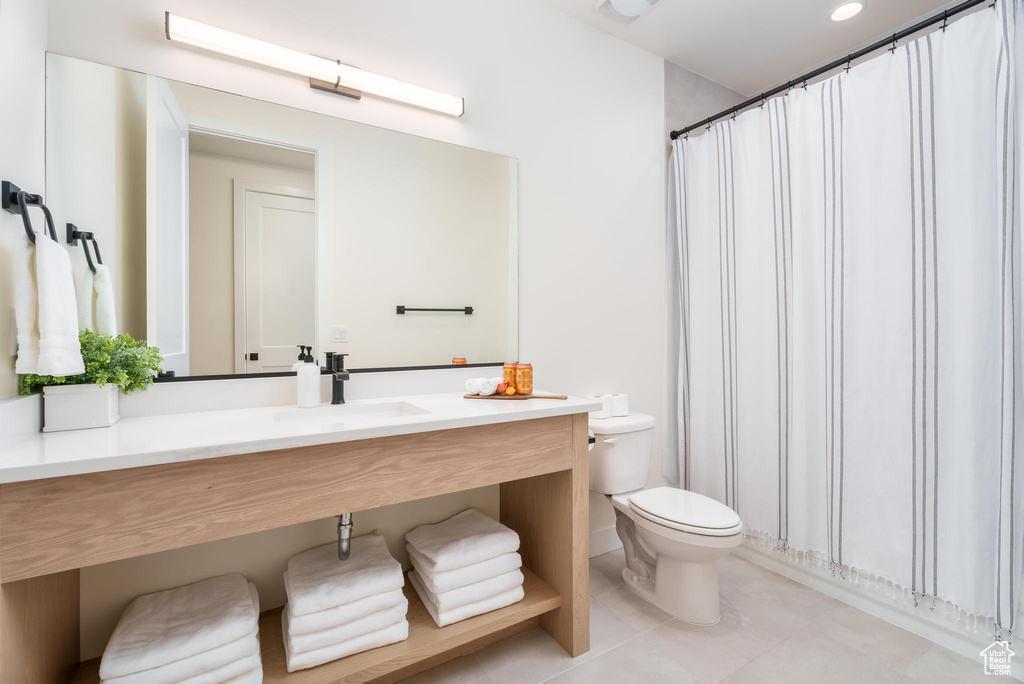 Bathroom featuring toilet, vanity, tile patterned floors, and a shower with shower curtain