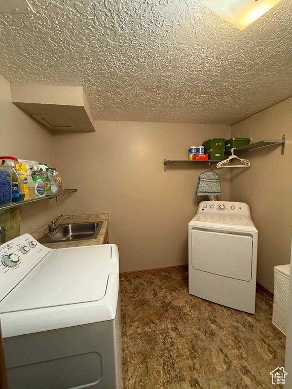 Washroom with washing machine and clothes dryer, a textured ceiling, and carpet floors