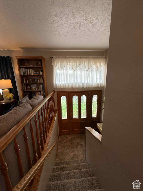 Stairs featuring a textured ceiling and carpet floors